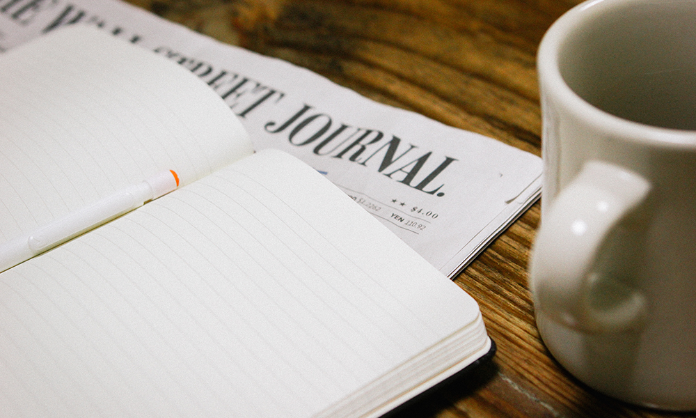 Journal, newspaper, and a mug of coffee