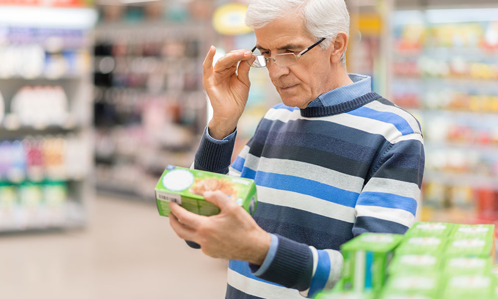 Older gentleman  reading the nutrition facts on the back of a food product