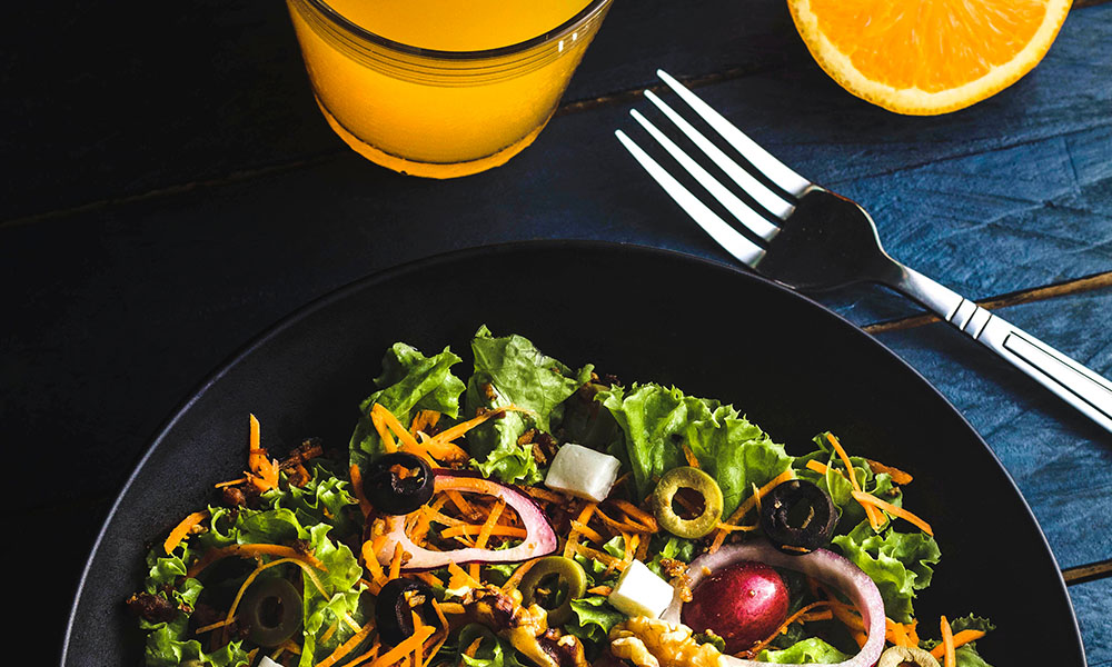 Greek kale salad with quinoa and chicken served with orange juice