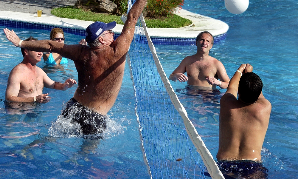 Group of older men playing pool volleyball on vacation
