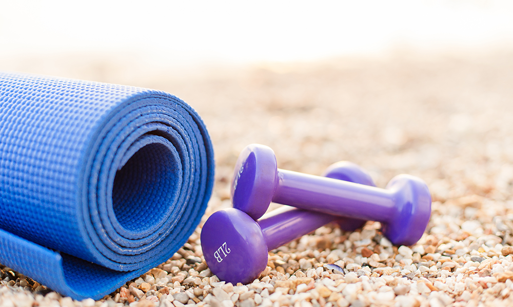 Yoga mat and dumbbells on the beach
